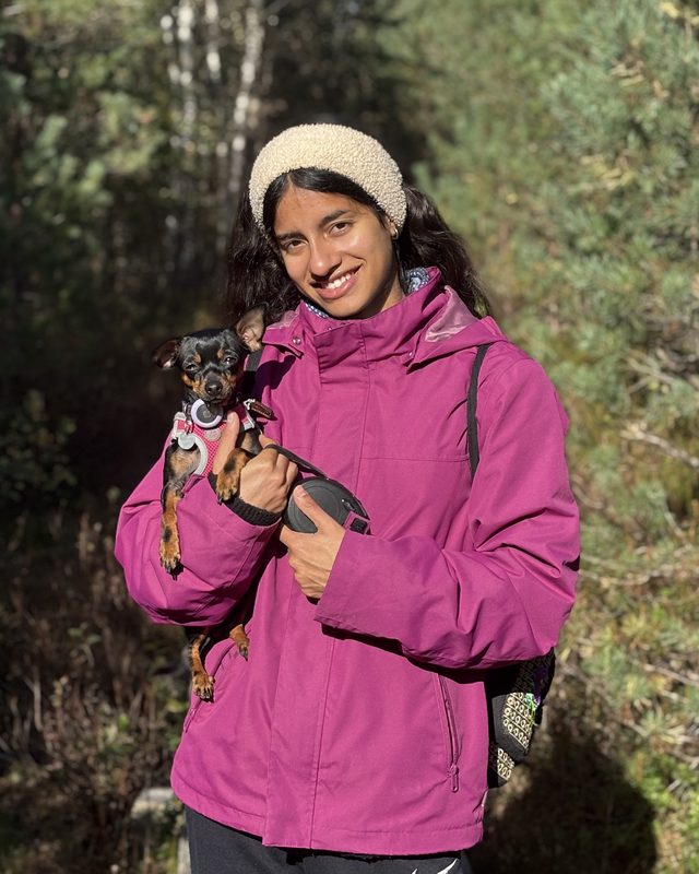 Valentina, founder of Baltibe Creative, holding her tiny dog Palmita on a forest trail